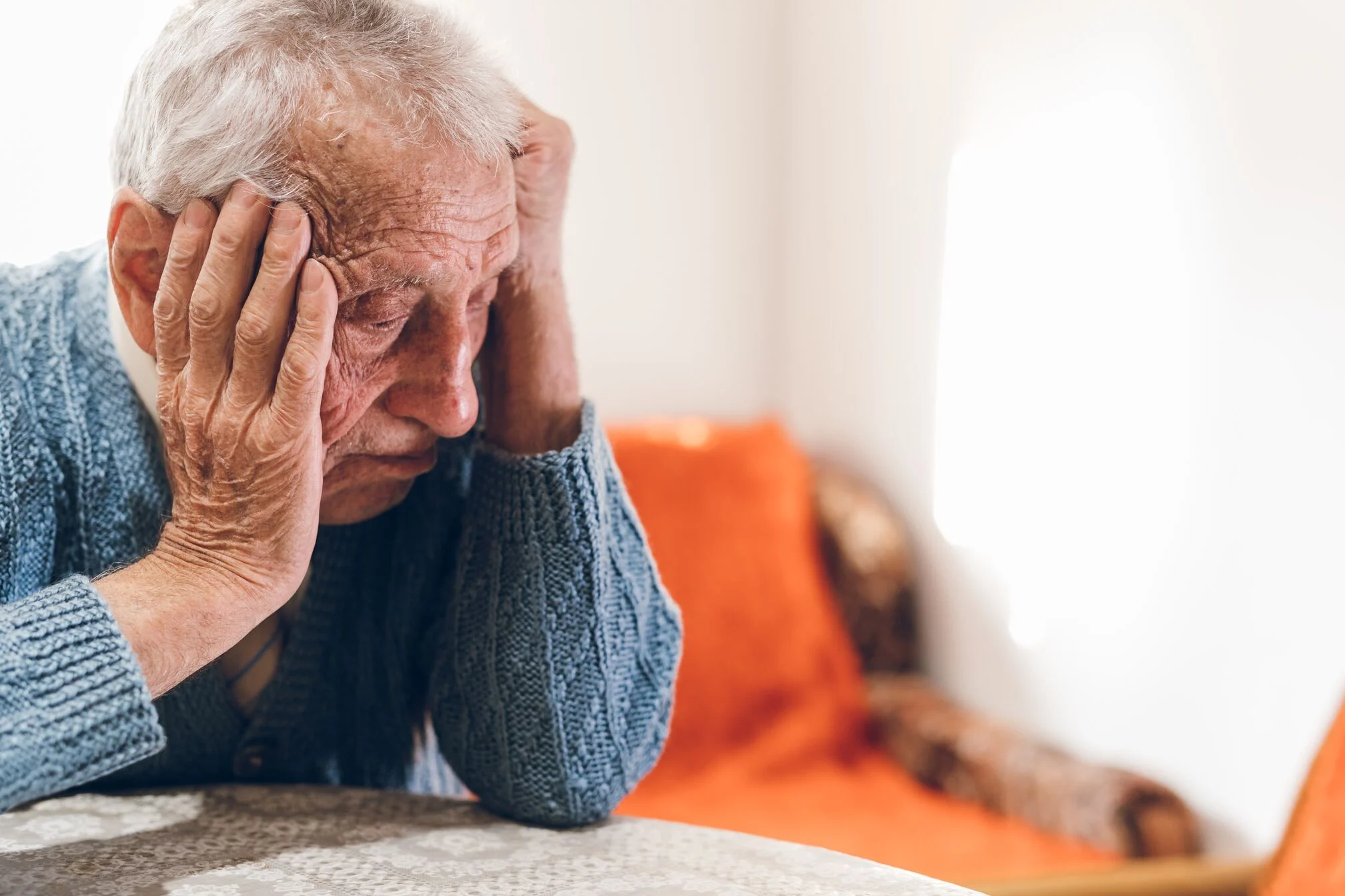 Older man head in hands sitting a table
