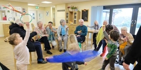 older people and children standing in a circle playing together