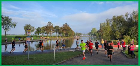 People running around the duck pond at Pontefract Racecourse ParkRun on a sunny day