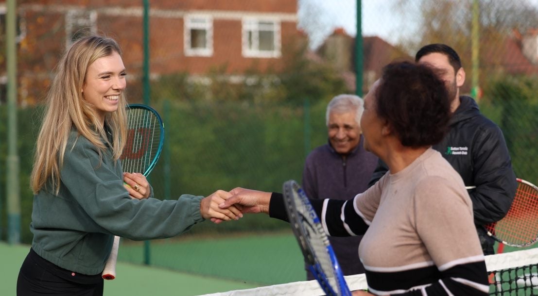 Tennis player Katie Boulter shaking hands with a lady on a tennis court