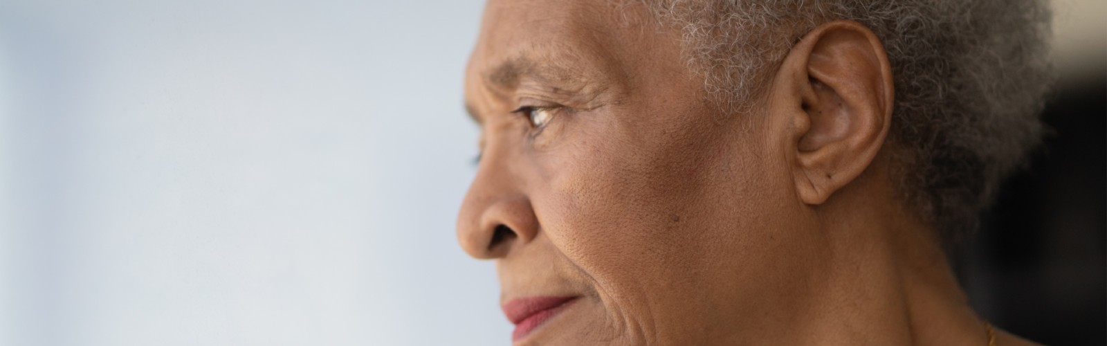 An older woman looks out of her window