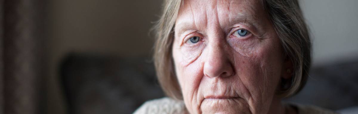 Older woman sitting on sofa looking into camera