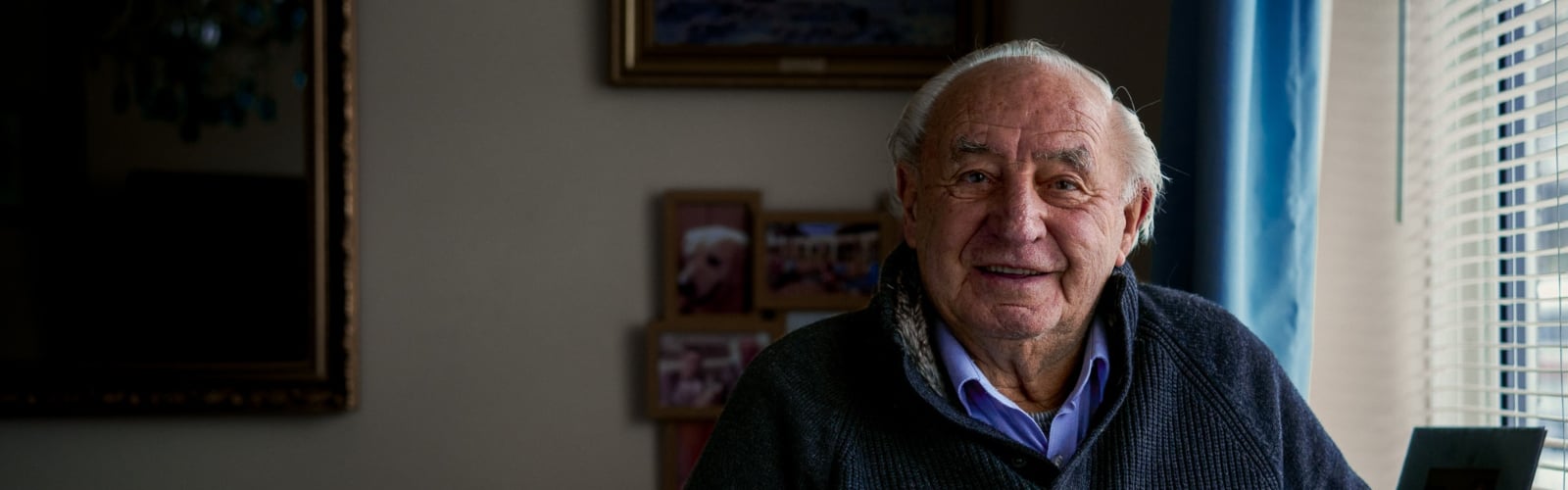 An older man with silver hair smiles at the camera