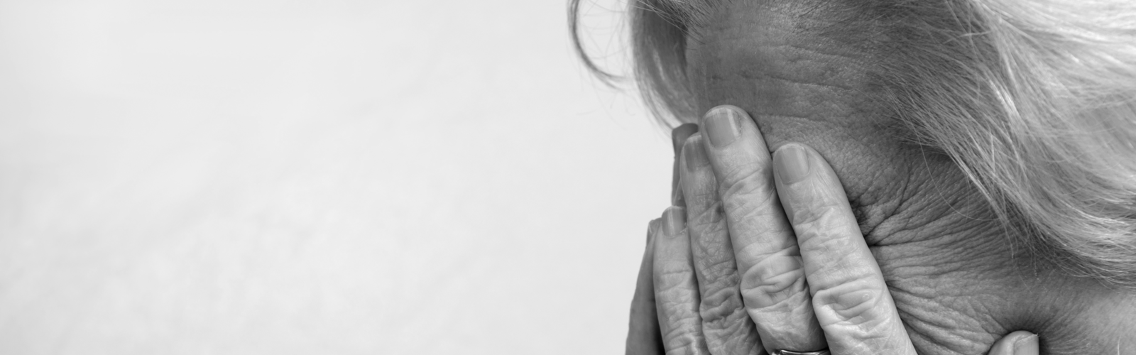 A black and white picture of an older woman with her head in her hands