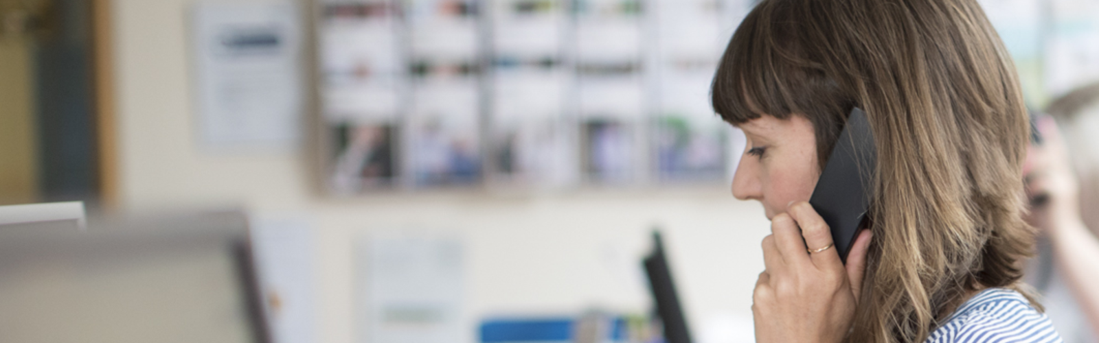 A woman  working at the Age UK Advice Line, wearing a headset