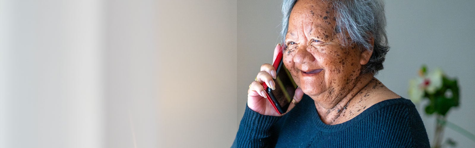 An older woman, smiling, speaking on the phone