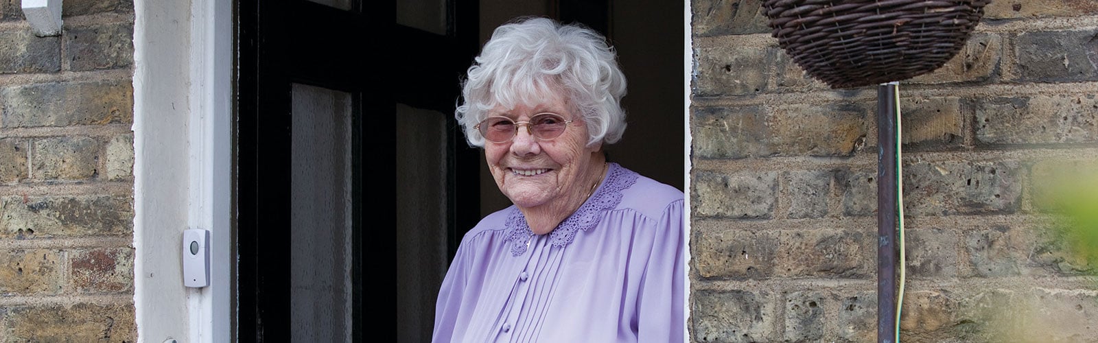 An older lady with a scarf on sat in a kitchen