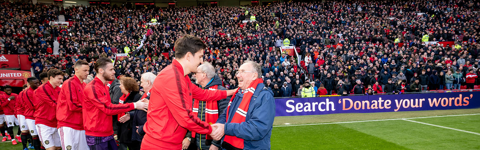 Manchester United players shaking hands with a group of older men and women