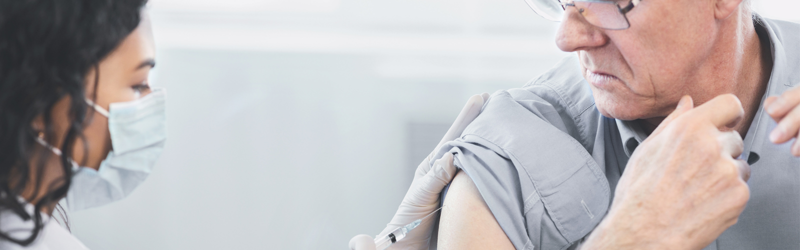 A doctor gives an injection to an older man.