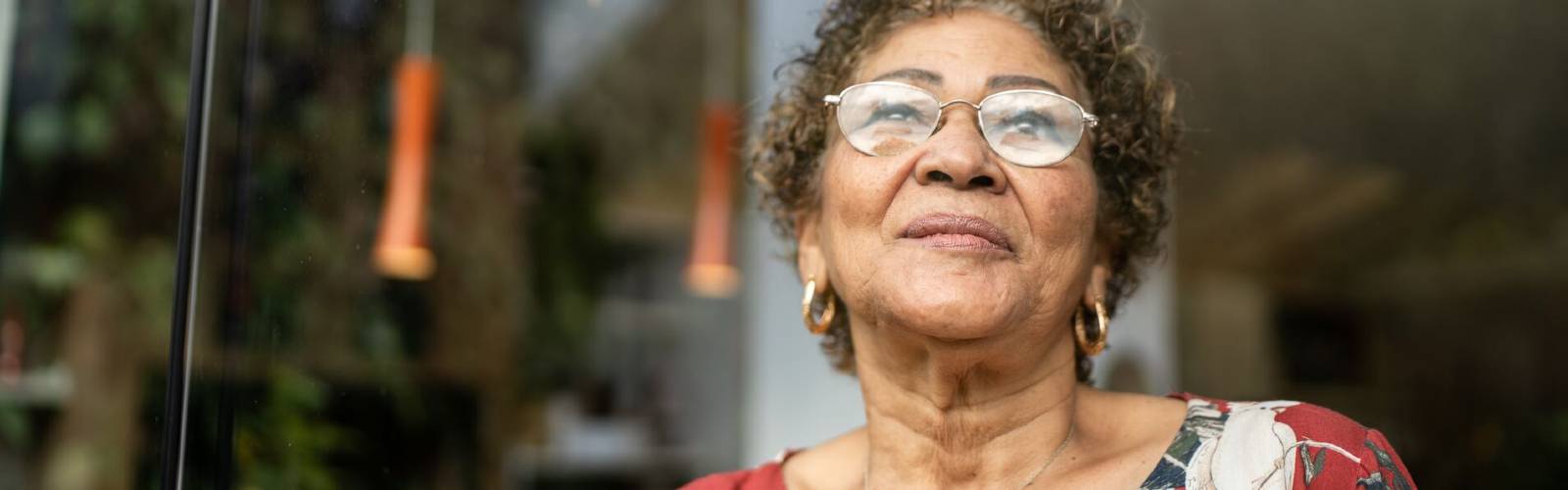 An older woman, wearing glasses, looking upwards