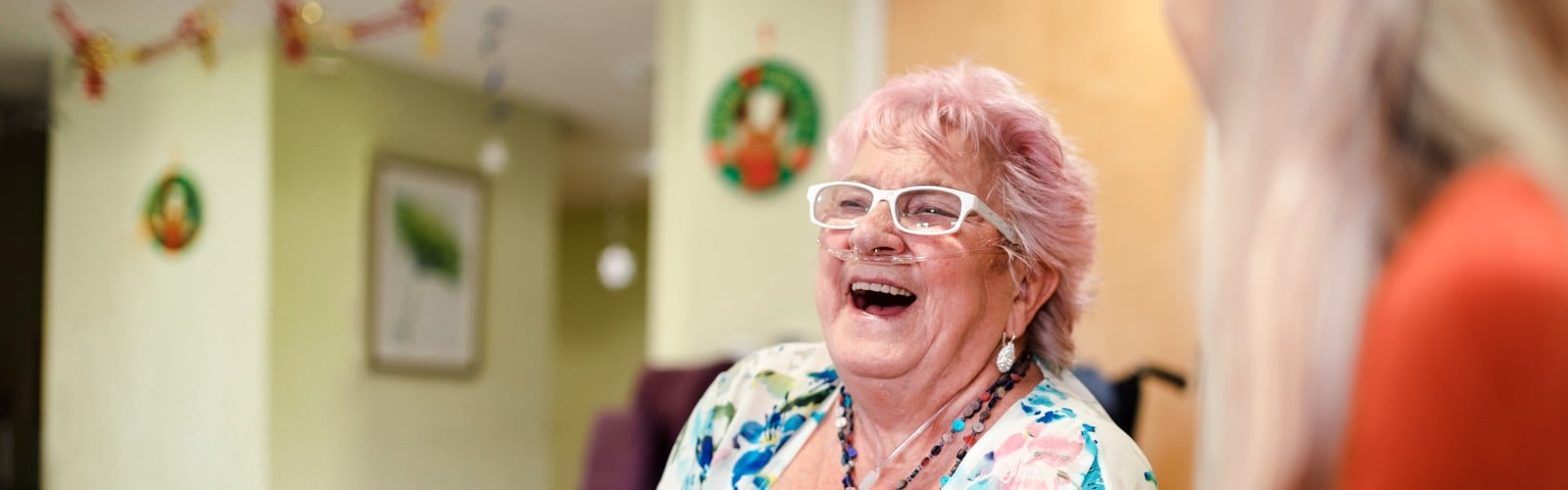 An older woman with an oxygen canula, laughing 