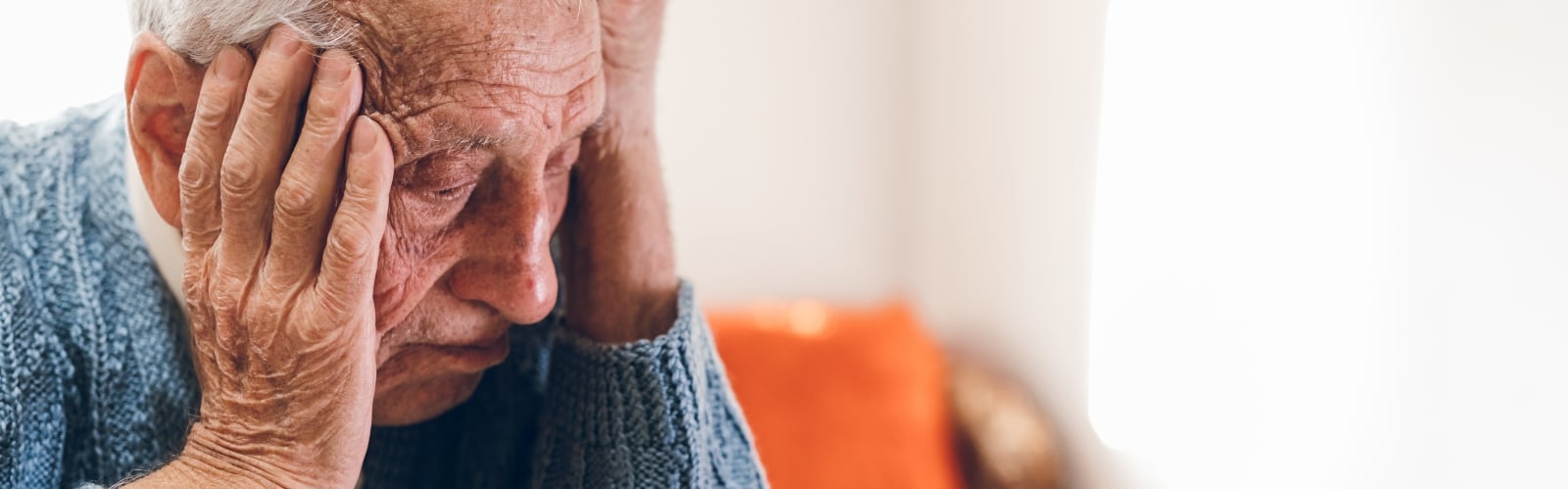 An older man looks sad with his head in his hands