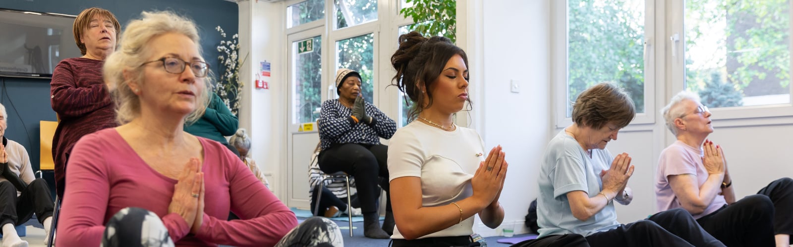 A group of women sit on mats practising yoga