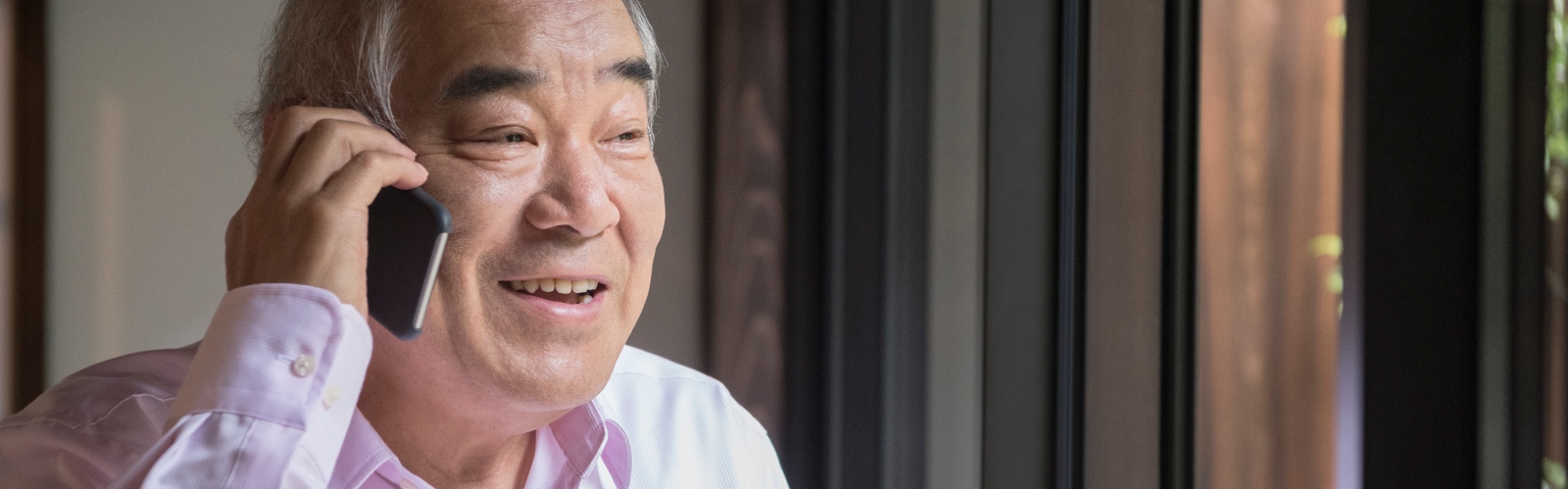 An older Asian man talks on the phone, smiling