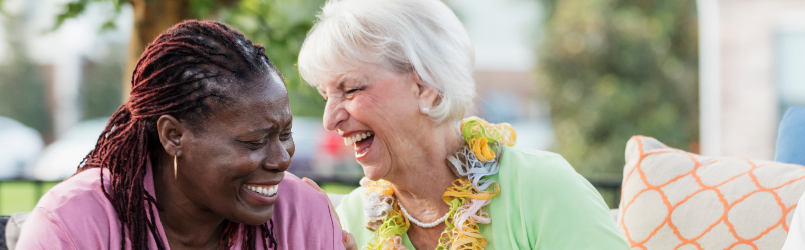 Two women, drinking tea together,  share a joke