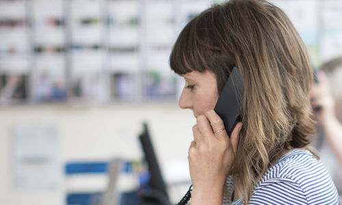 A woman  working at the Age UK Advice Line, wearing a headset