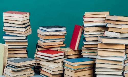 Multiple stacks of books against a teal background