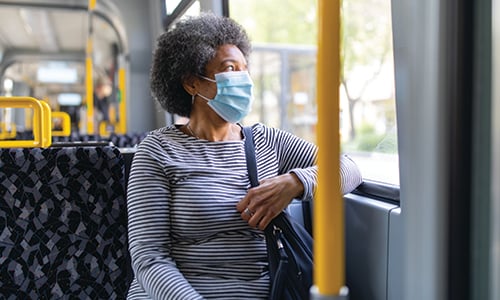 A woman sat on a bus wearing a face covering