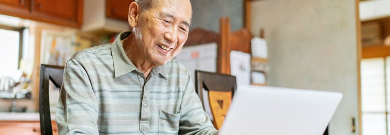 Man smiling using a laptop to send an email