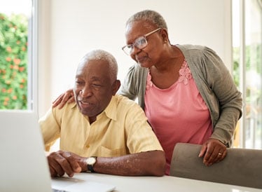 Couple smiling at the laptop whilst on a video call