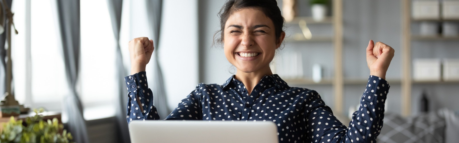 a young woman celebrating a lottery win at her computer