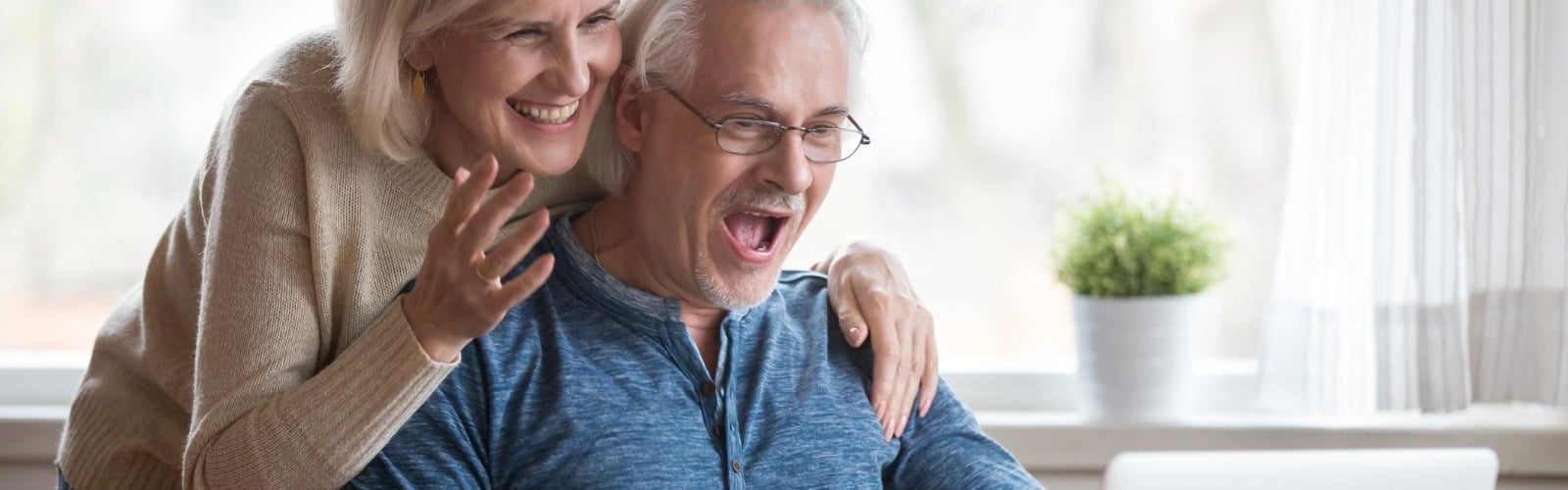 : man and women looking at a computer screen looking excited